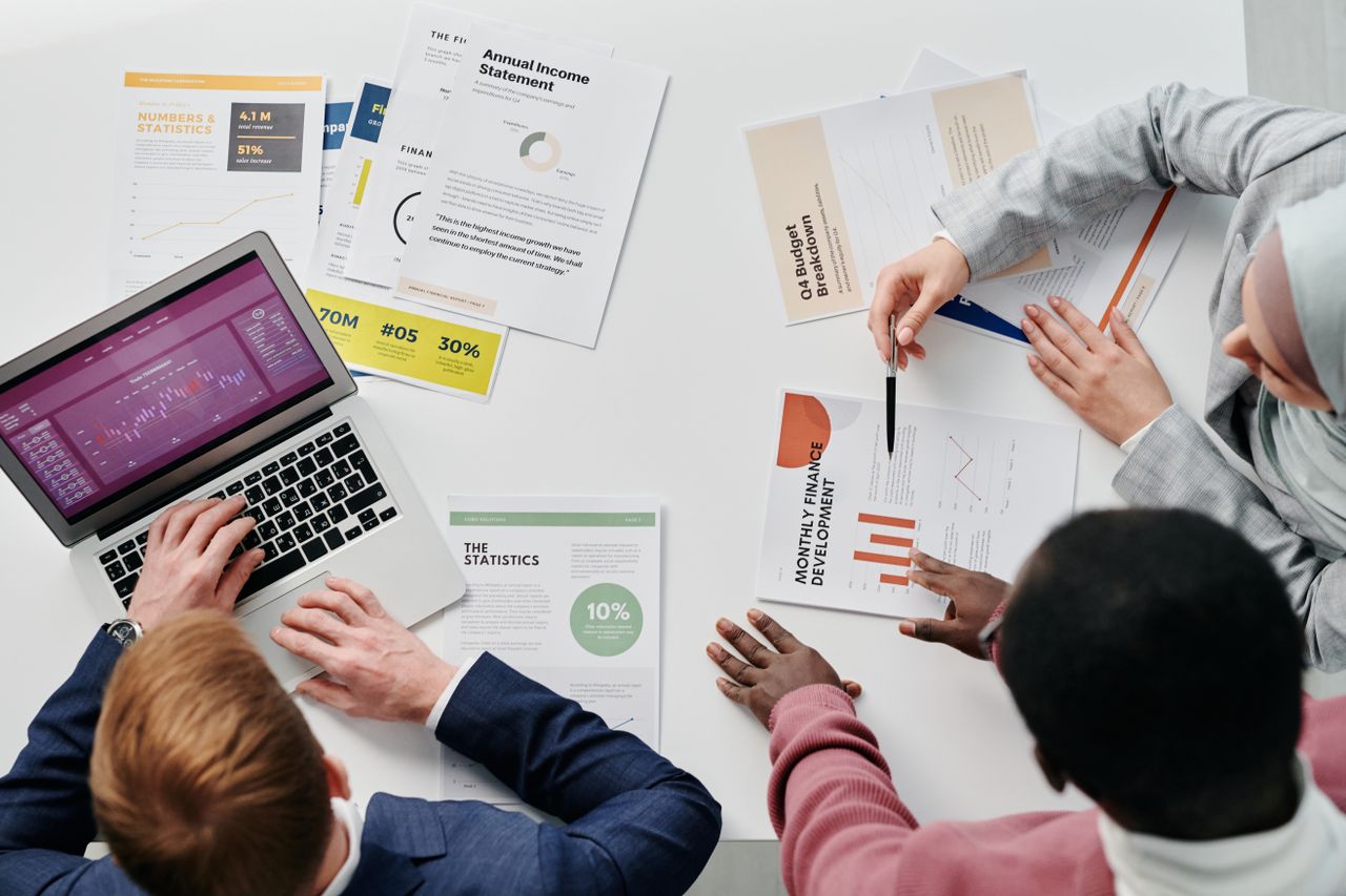 Business meeting with professionals discussing financial reports and graphs at a work desk.